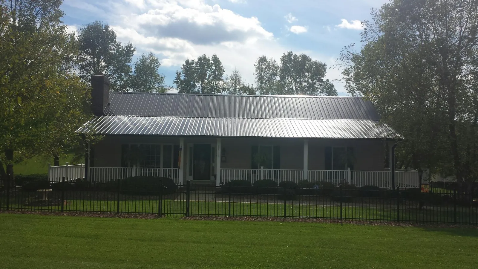 Gray metal roof on a brick ranch with a full width front porch — Gutter Guard Installation work by our crew in Nederland