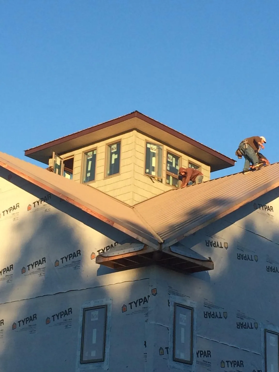 Roofers working around a rooftop cupola on a new metal roof at sunset — Roof Waterproofing in Nederland by Roofing Brothers